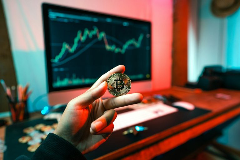 A person holding a coin in front of a computer