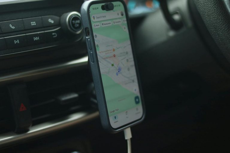 A smartphone with a map app displayed inside a car, showing modern navigation.